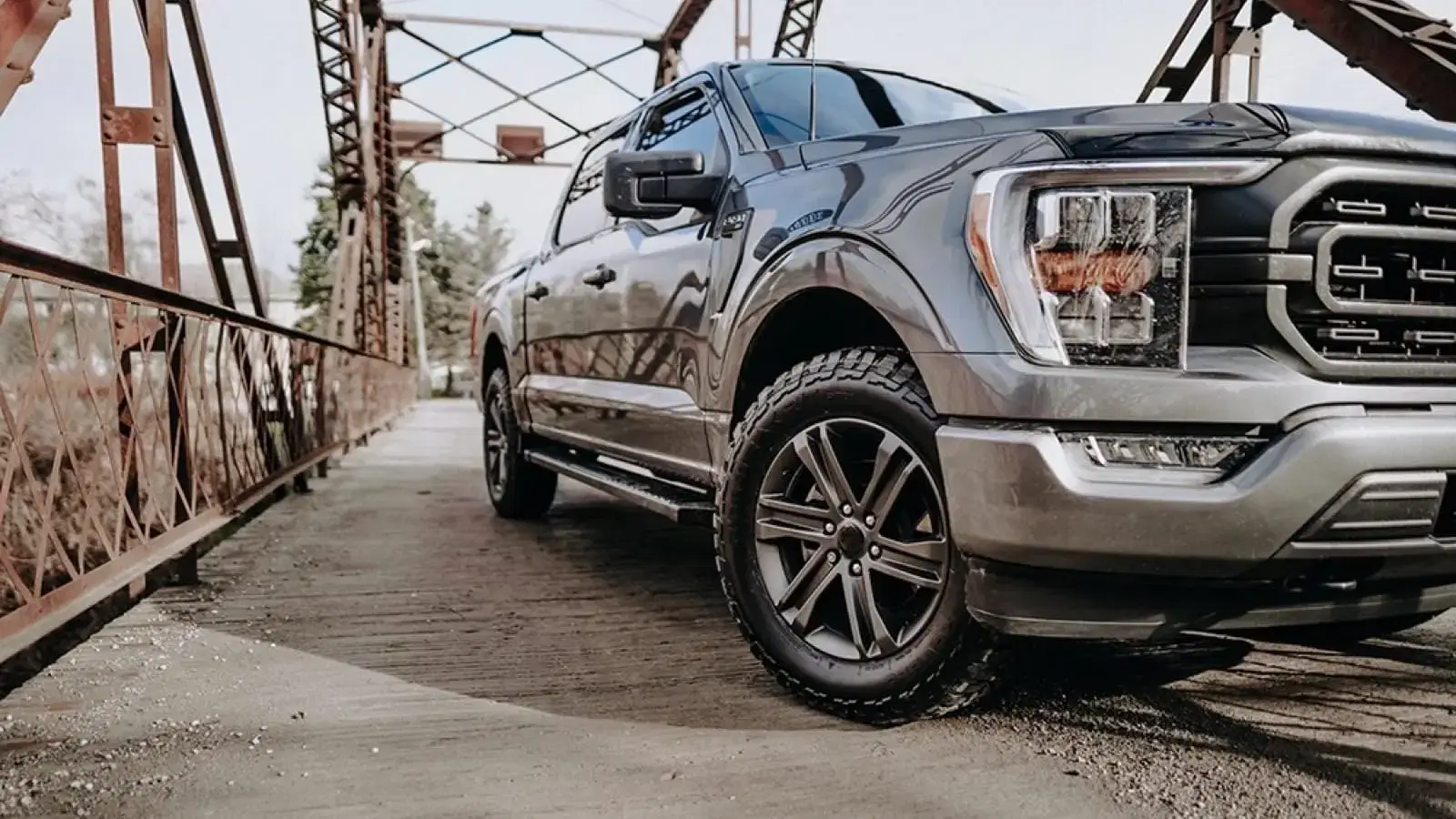 Tough truck with all terrain tires parked on rustic bridge, ready for adventure in rugged terrain