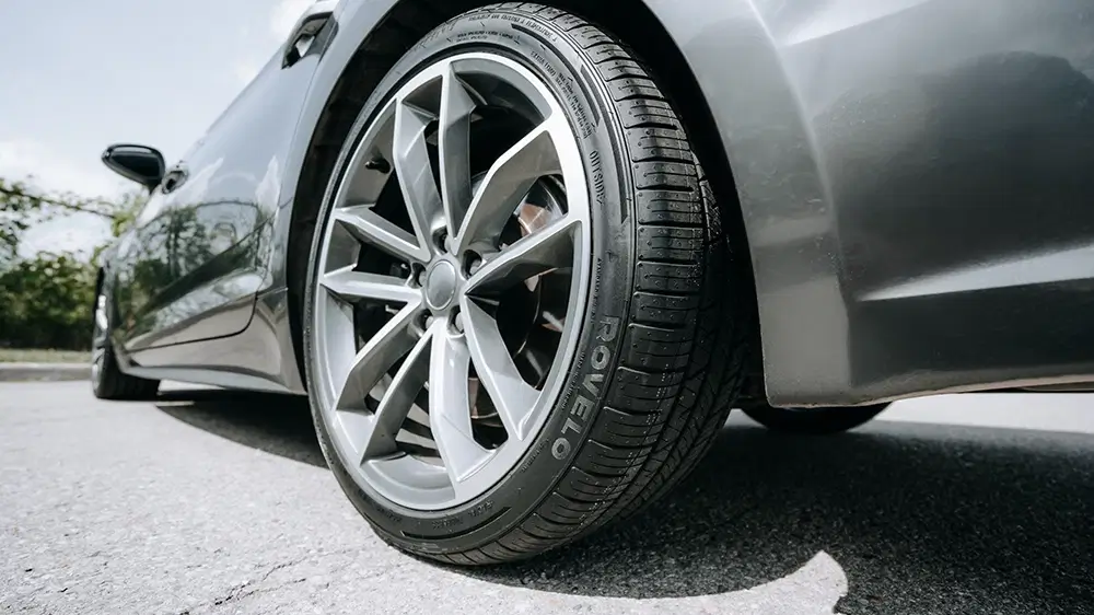 Sports car with Rovelo performance tires parked on asphalt, showcasing modern wheel design and tread pattern.