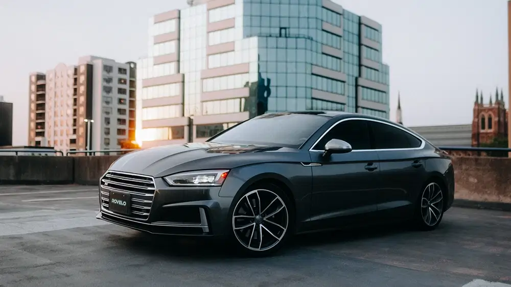 Sleek sedan parked on rooftop with modern buildings in the background, showcasing stylish performance tires.