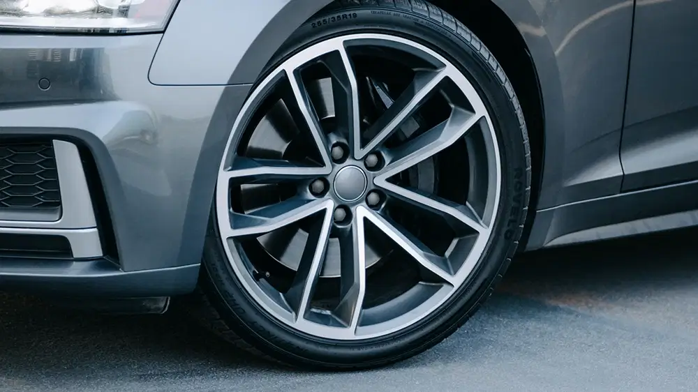 Close-up of sleek performance tires on a modern sports car, showcasing advanced tread design and stylish rim.