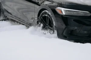 Tire on black car driving through thick snow